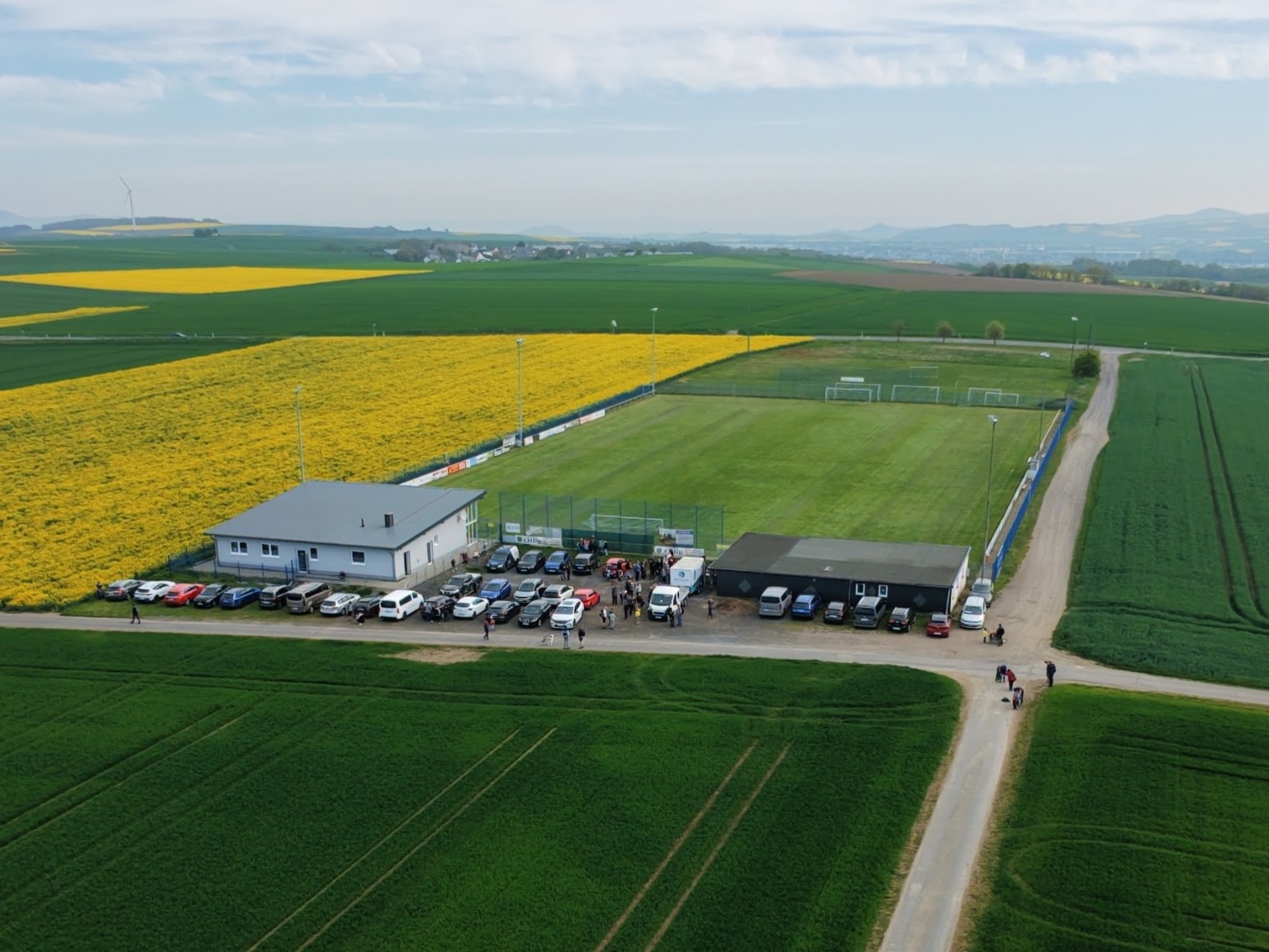 Luftaufnahme der Elztaler Alm mit Spielfeld, Vereinsheim und umgebenden Rapsfeldern